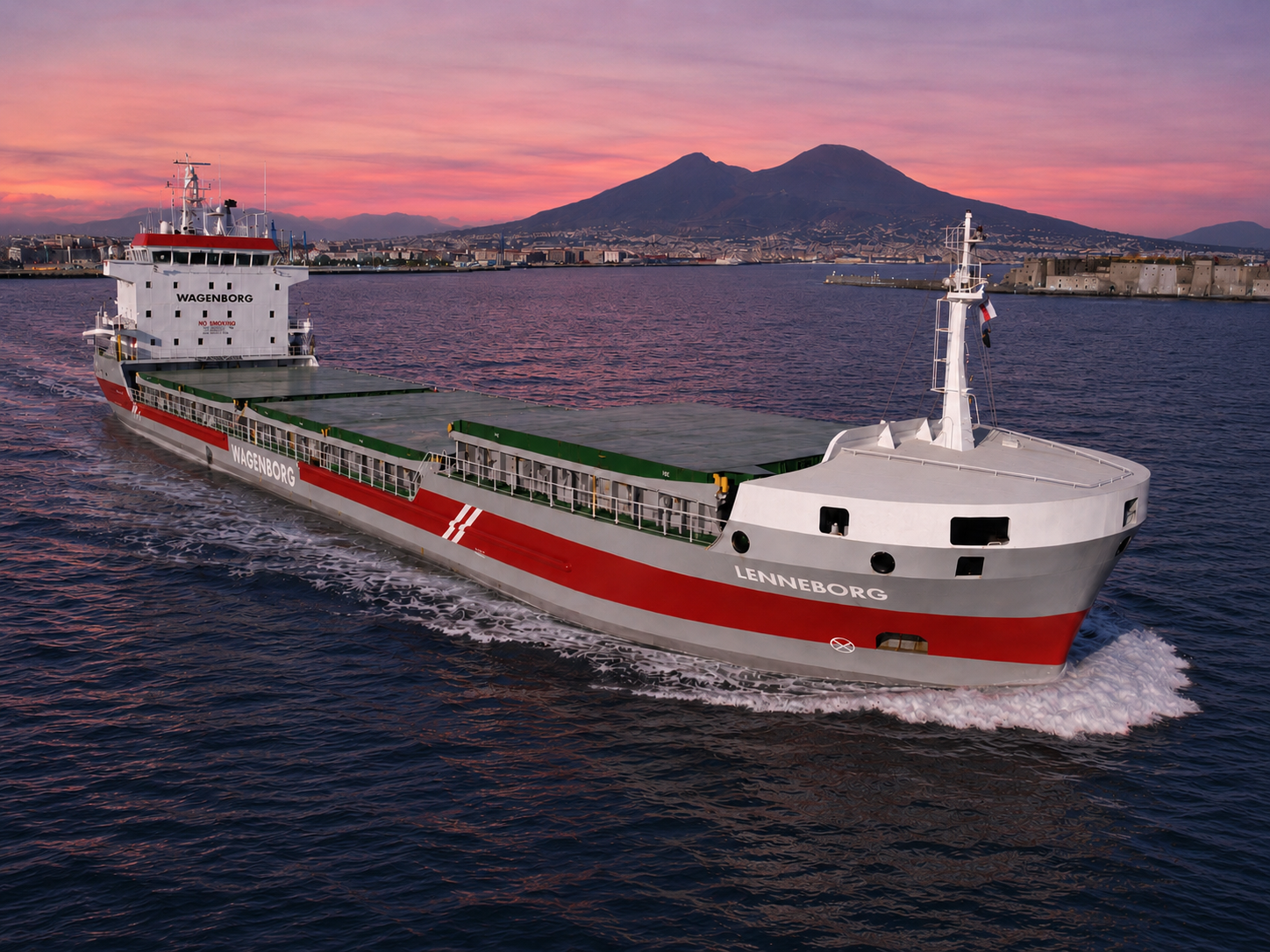 Shortsea general cargo vessel with box-shaped holds and folding hatch covers under way in the Bay of Naples at sunset, Vesuvius in the background.
