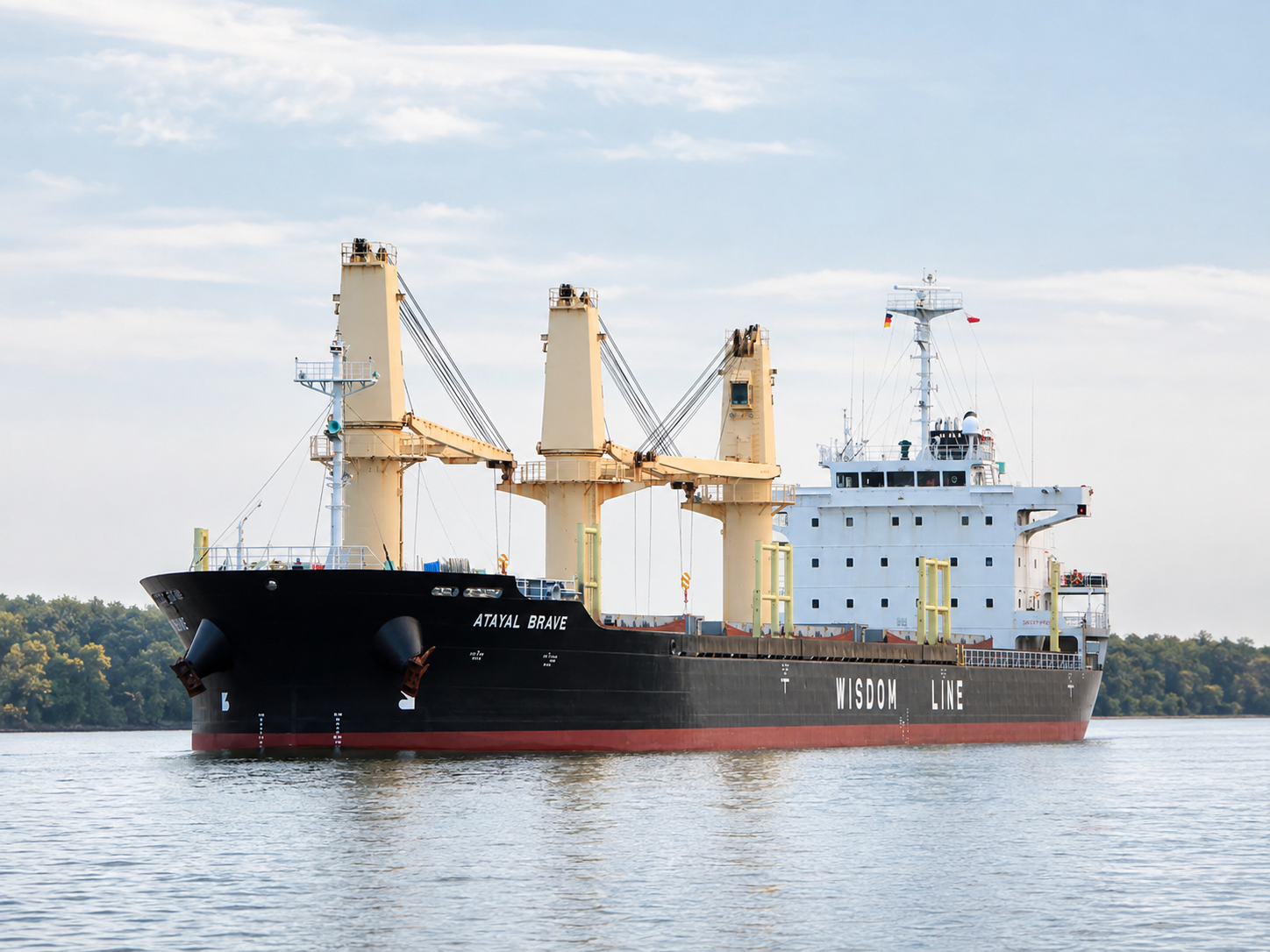 Geared bulk carrier ATAYAL BRAVE of Wisdom Line under way on a calm river, deck cranes and black hull.